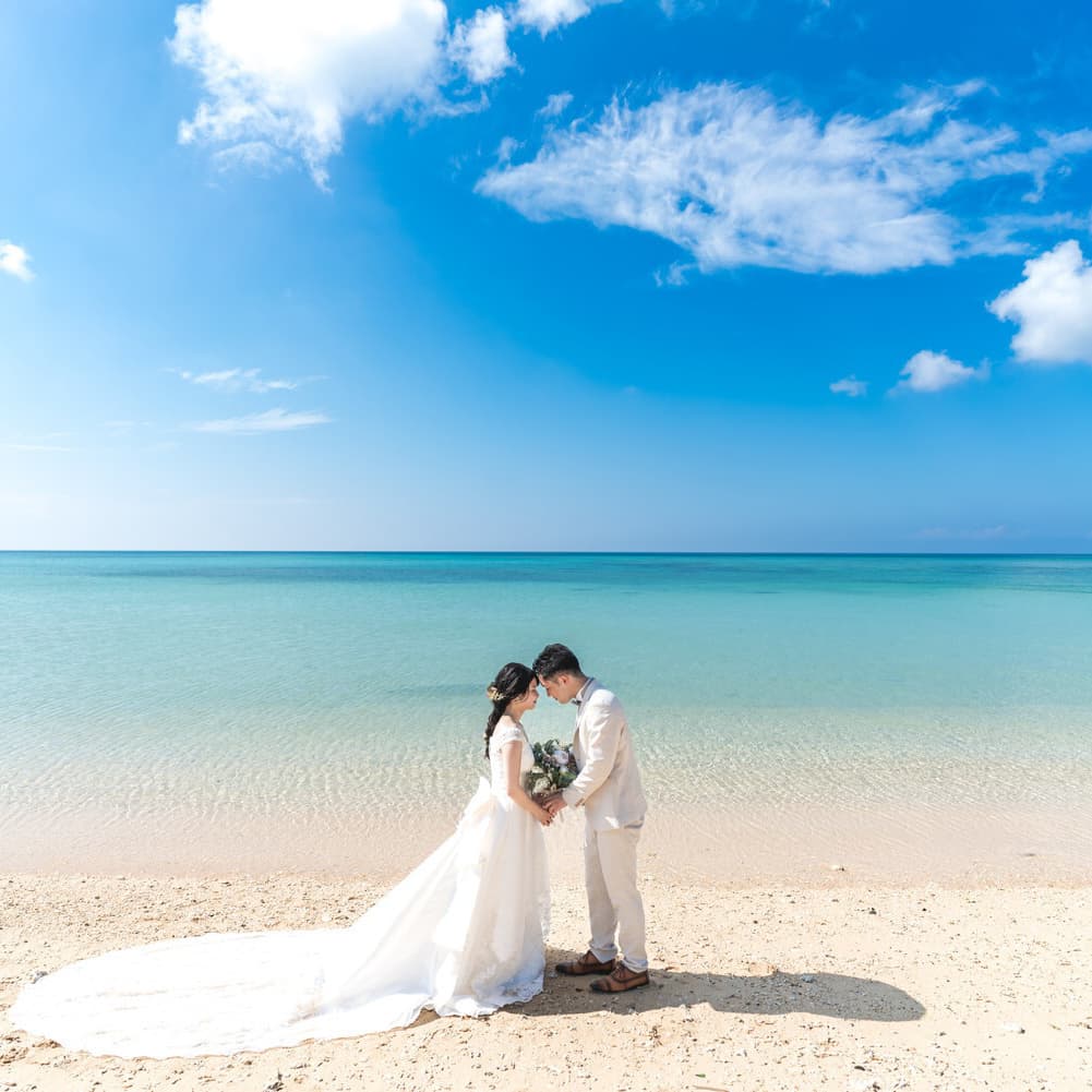 石垣島の海を背景に向かい合わせで顔を寄せ合う新郎新婦