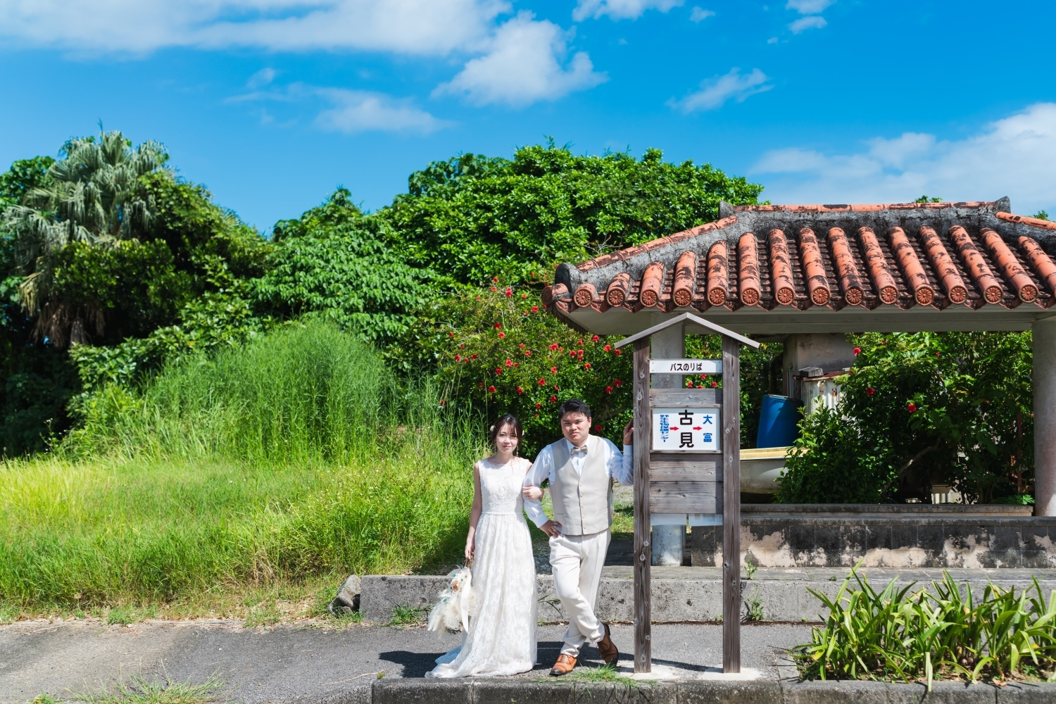 西表島のバス停に立つ新郎新婦