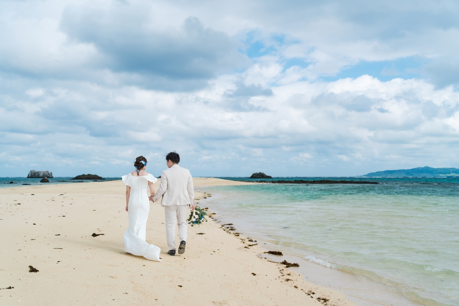 幻の島で砂浜を歩く新郎新婦の後ろ姿