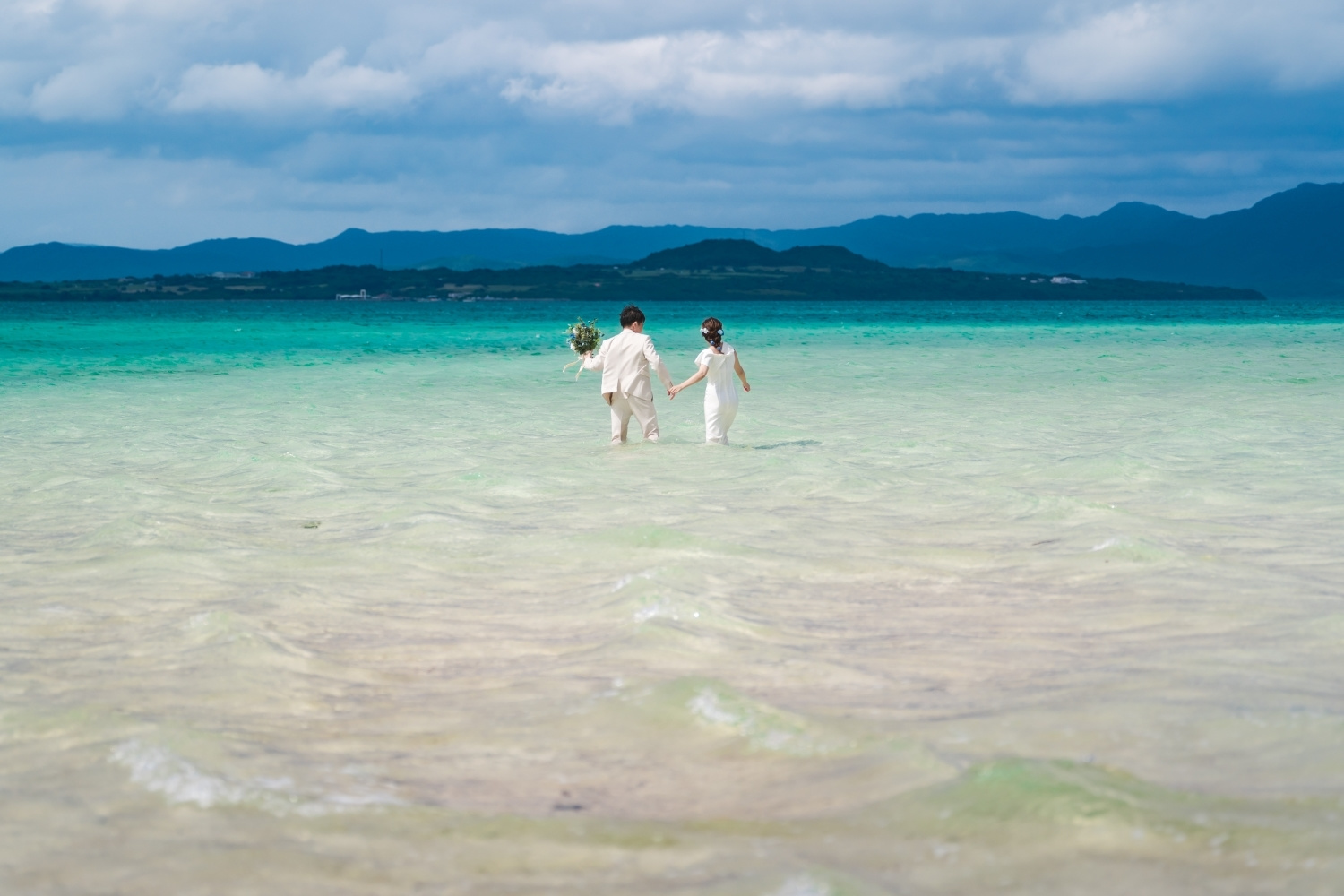 海に入っていく新郎新婦の後ろ姿